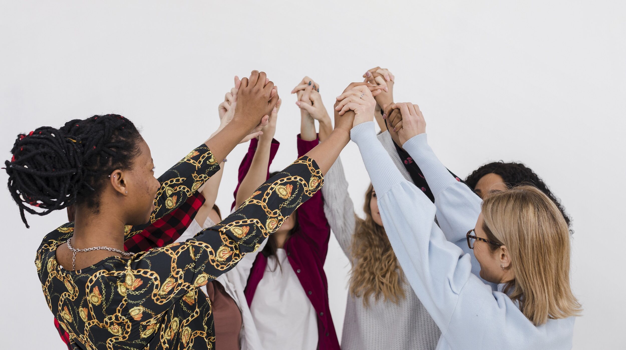 Mulheres de diferentes etnias juntas dando as mãos