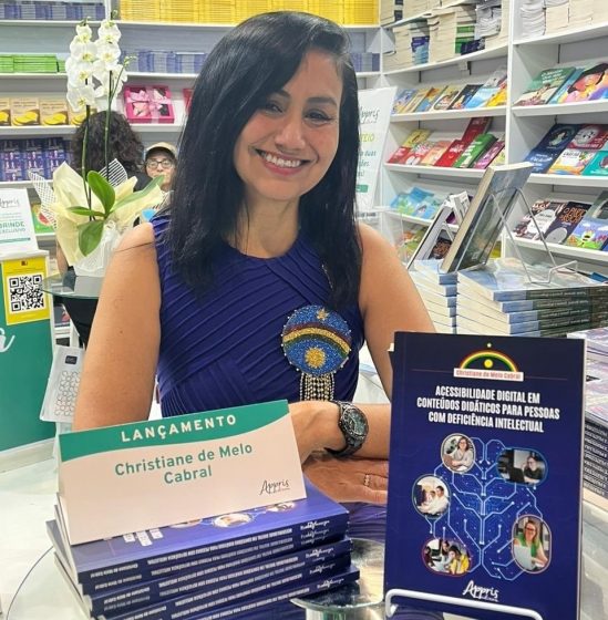 Christiane Cabral sentada atrás de seus livros